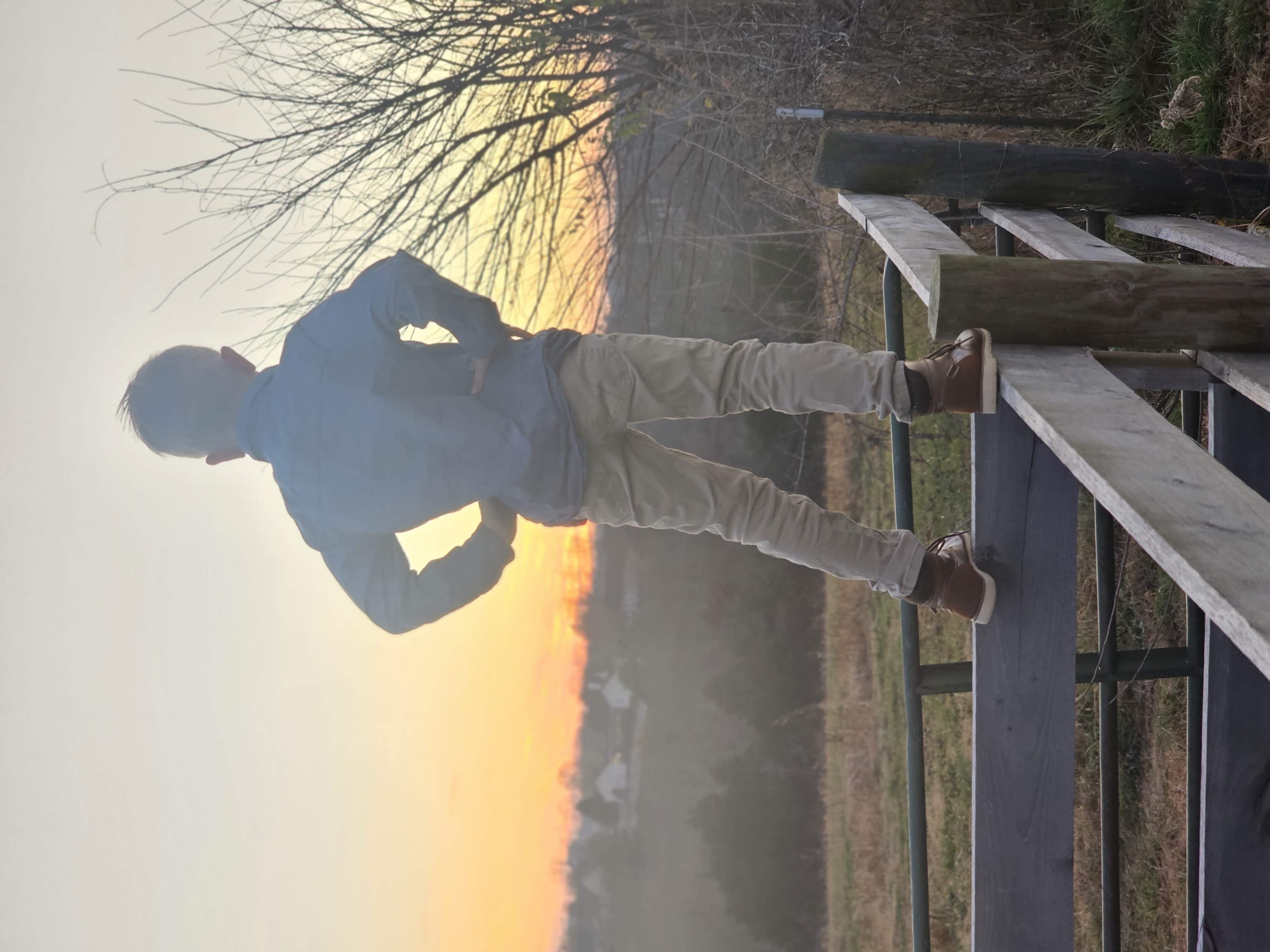 Leland standing on the farm fence at sunset
